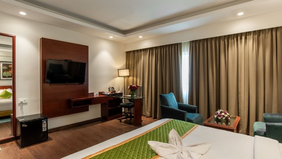 Modern guest room with bed, television, and comfortable seating at Hotel Royal Regency Chennai