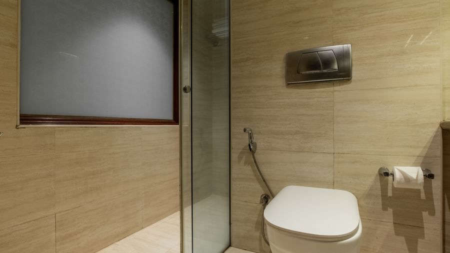 Bathroom with glass shower enclosure, toilet, and tiled walls at Hotel Royal Regency Chennai