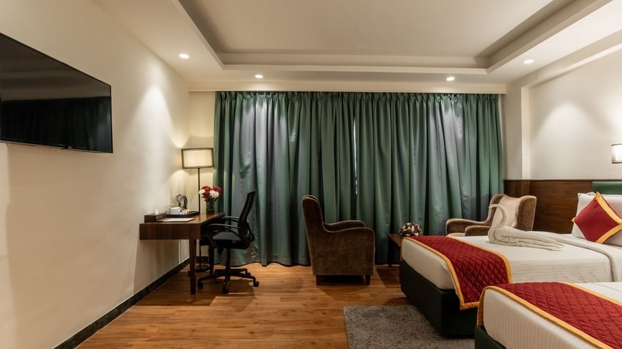 Twin bedroom with curtains and reading lamp at Hotel Royal Regency Chennai