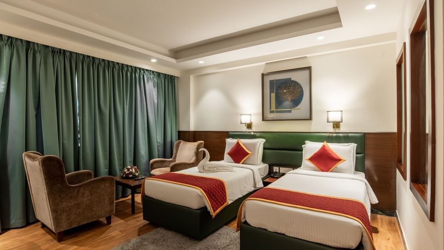 Spacious twin bedroom with comfortable seating and decor at Hotel Royal Regency 
