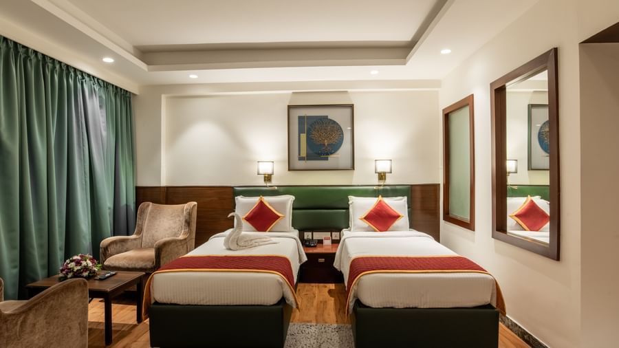 Room with twin beds, armchairs, and framed artwork at Hotel Royal Regency Chennai