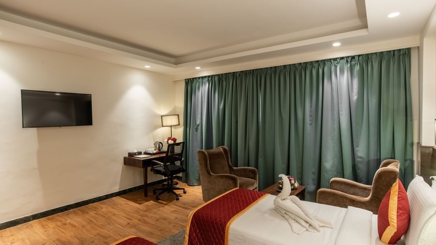Modern guest room with television, desk, and seating area at Hotel Royal Regency Chennai