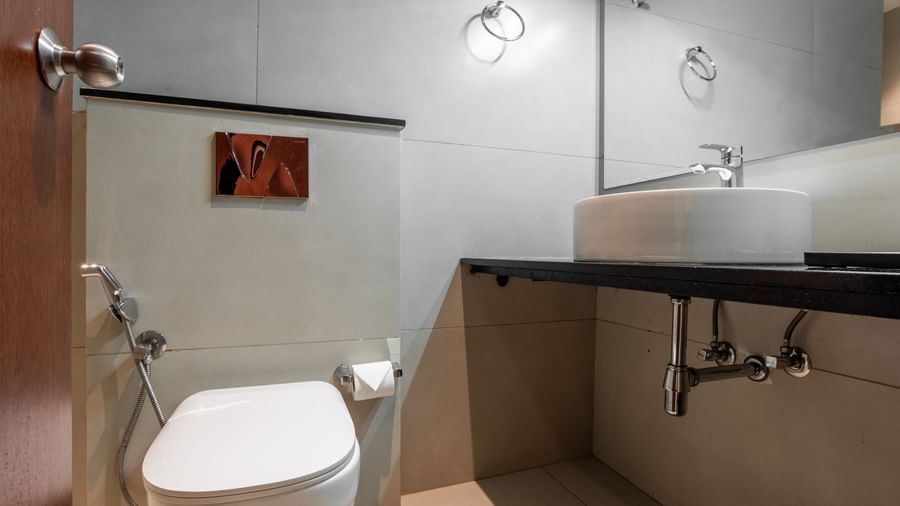 Modern bathroom with toilet, washbasin, and wall mirror at Hotel Royal Regency Chennai