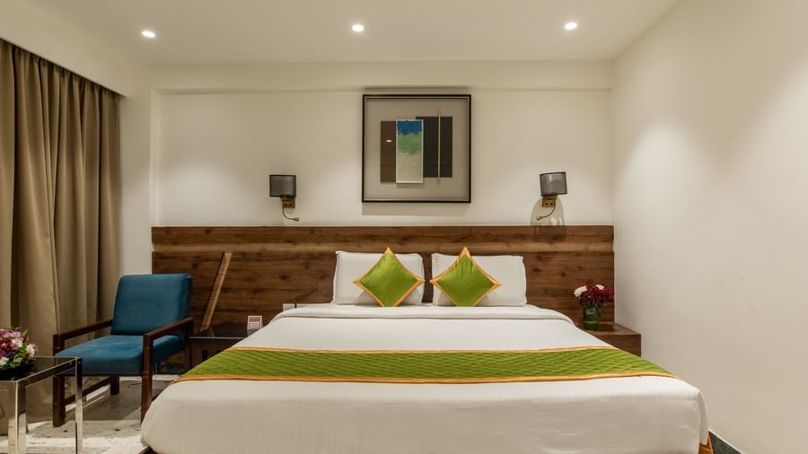 Guest room with king size bed, seating area, and framed artwork at Hotel Royal Regency Chennai