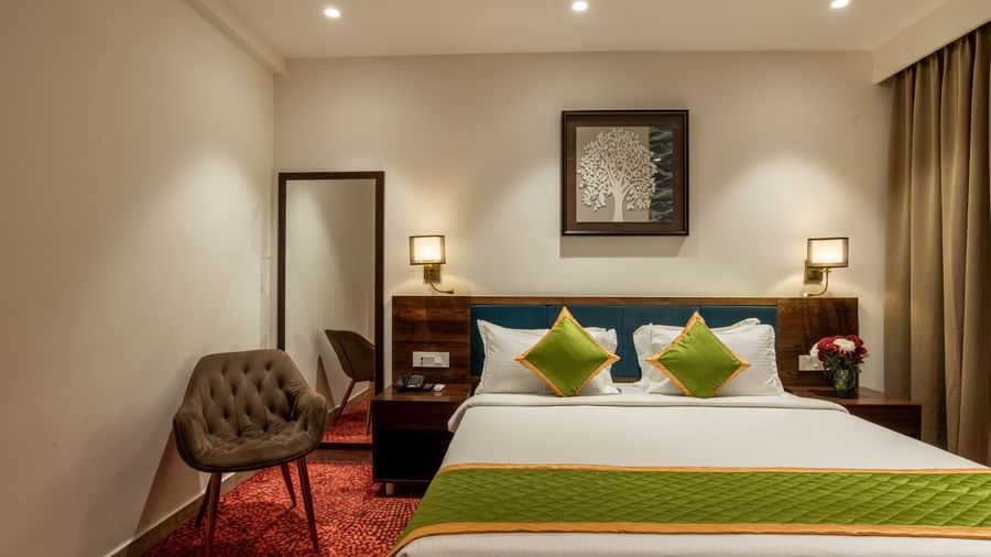 Bedroom with king size bed, wooden furniture, and warm lighting at Hotel Royal Regency Chennai
