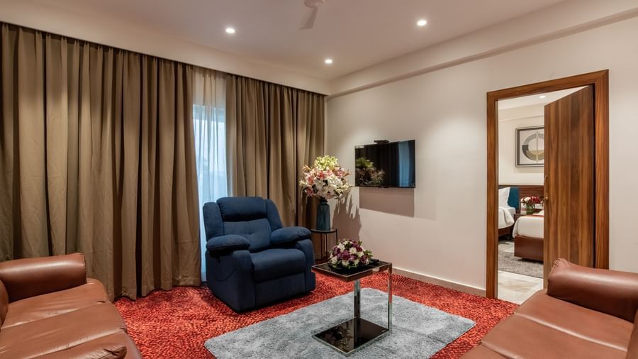 Comfortable lounge area with sofas, armchairs, and TV in a suite at Hotel Royal Regency Chennai