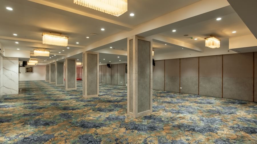 Spacious banquet hall with carpet flooring and chandeliers at Hotel Royal Regency Chennai