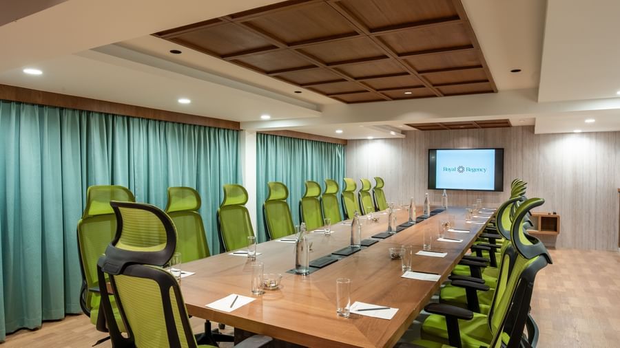 Modern boardroom with long table and green chairs at Hotel Royal Regency Chennai