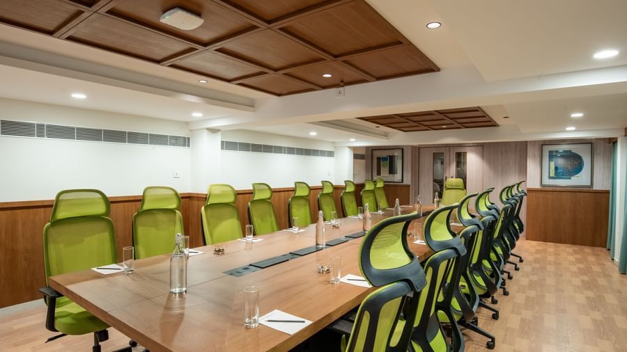 Conference room with long wooden table and green chairs at Hotel Royal Regency Chennai