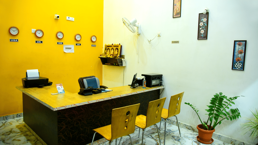 Reception of Housefinch Residency featuring a reception desk against a wall with 5 clocks facing 3 chairs 