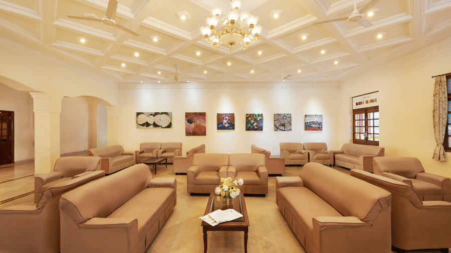 A spacious hotel lobby lounge with comfortable brown sofas and a large crystal chandelier - Jenneys Residency, Coimbatore