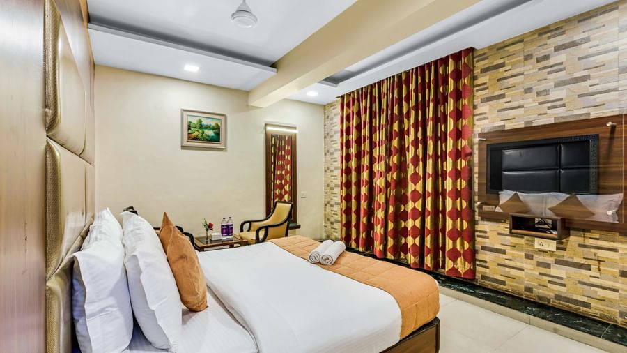 A brightly lit executive room in Krushnai Resort featuring a double bed with white lnen and yellow runner.