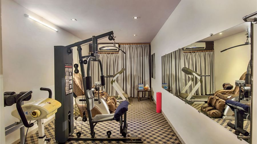 A compact hotel gym with various exercise machines and mirrored walls - Lords Eco Inn Dahej