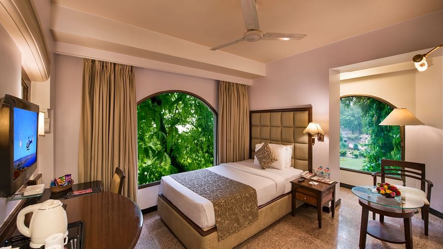 A hotel room at Lords Inn Vadodara featuring a single bed with a patterned runner, a wooden headboard, and bedside lamps. 
