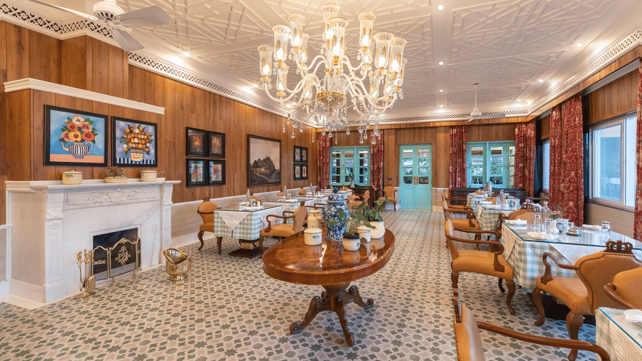 Grand chandelier lighting an elegant dining room with fireplace at Mayfair Manor, Jungpana.