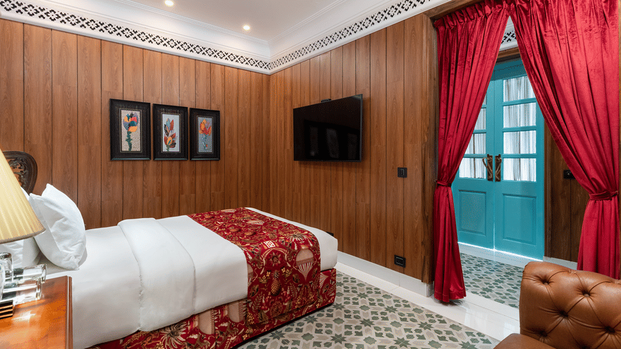 Cosy guest bedroom with red drapes and wood-panelled walls at Mayfair Manor, Jungpana.