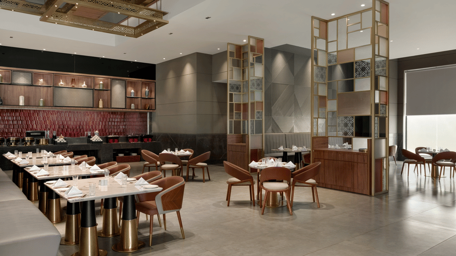 Bright and airy restaurant interior with neatly arranged dining tables, gold decorative dividers, and contemporary grey decor.
