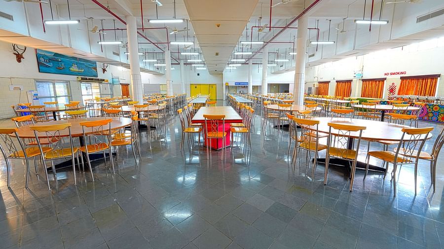 A cafeteria with many tables and chairs and a common table at the center at Sahara - Social Dining in Hyderabad.