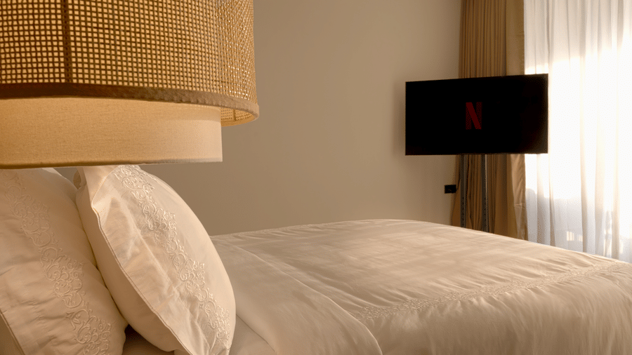 Hotel room at SUKAVI with a large bed,  curtains, and a wall-mounted television.