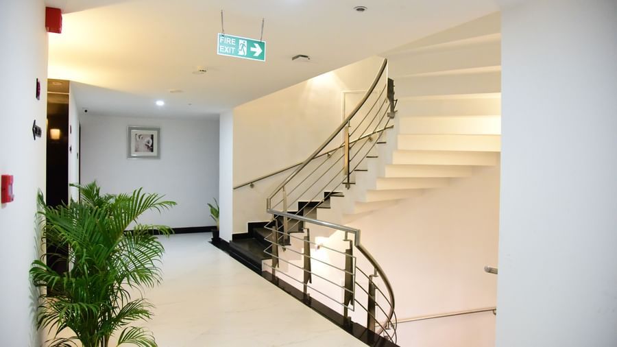 The interior lobby of The Royal Comfort, with a prominent white staircase and a plant in the corner, leading to the upper floors.
