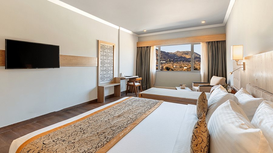 A close-up shot of a bed with a patterned runner on it and a tv mounted on the wall - Via Lakhela Resort & Spa, Kumbhalgarh