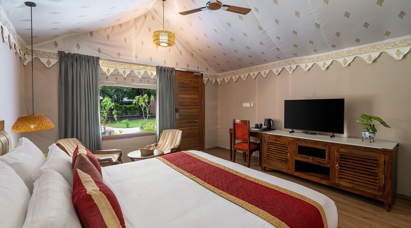 corner view of the luxury tent villa with a fan hanging from the ceiling featuring a plush king size bed at aranya vilas