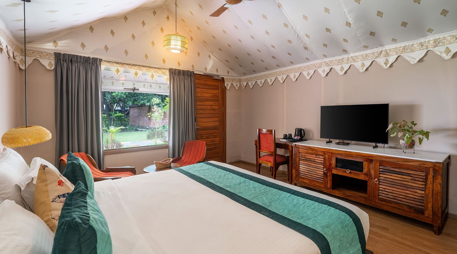 image of a beautiful luxury tent villa at aranya vilas featuring a king size bed with a tv table and television right opposite to it