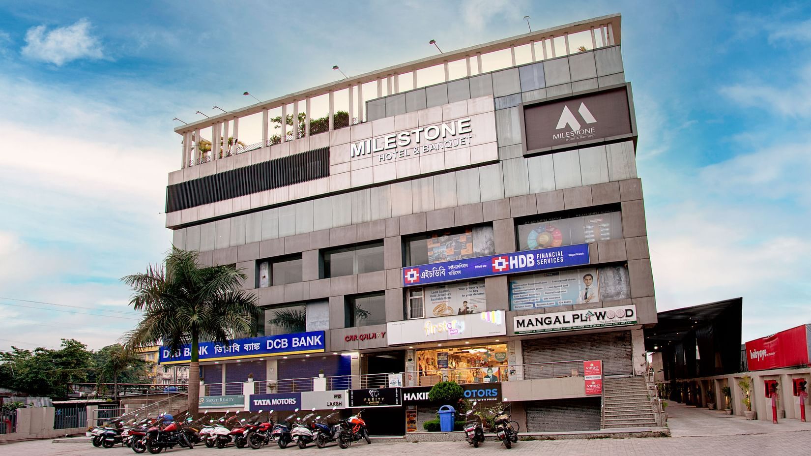 Exterior view of the multi-storey Voyage Milestone Hotel and Banquet Siliguri building with shops on the ground floor.