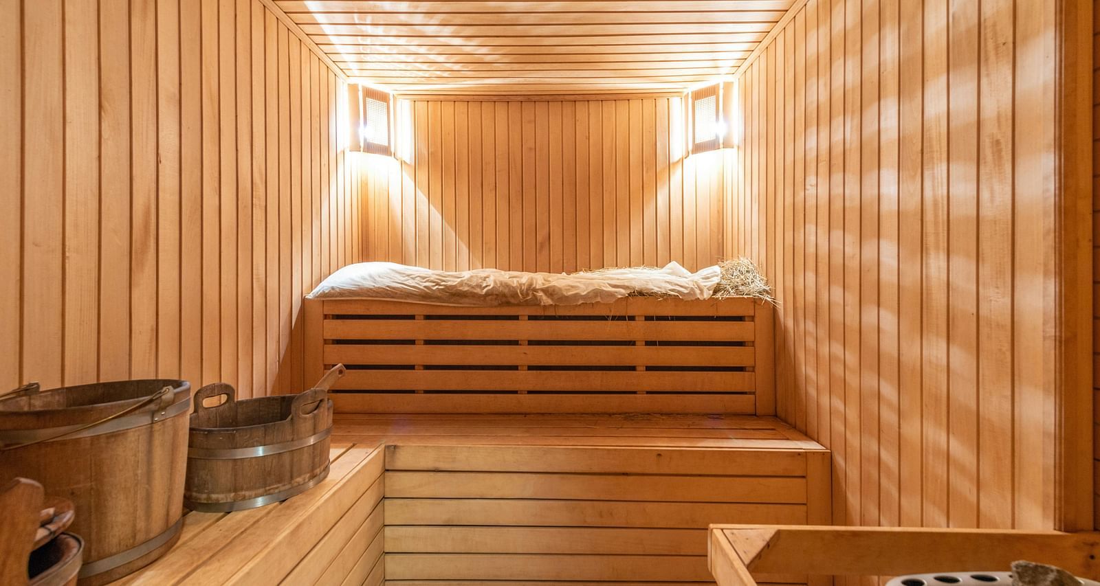 a wooden sauna room with two warm lights mounted in the corner of the ceilings