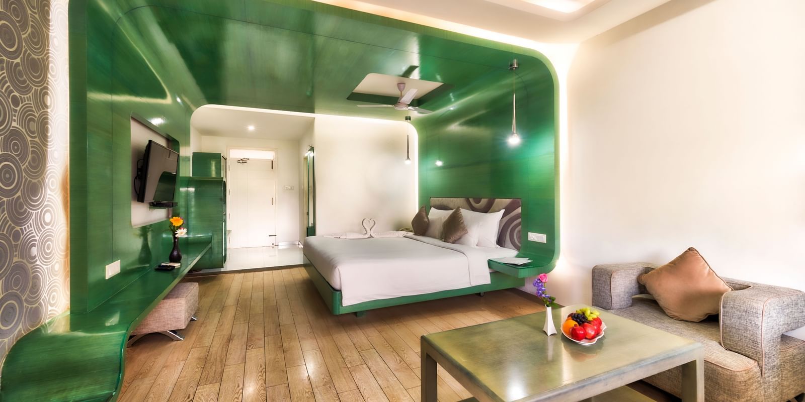 A room with king size bed, green wall panel and seating area at Grande Bay Resort & Spa.