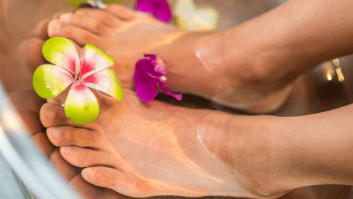 A beautiful feet on a bowl of rose water and flowers undergoing a spa treatment.