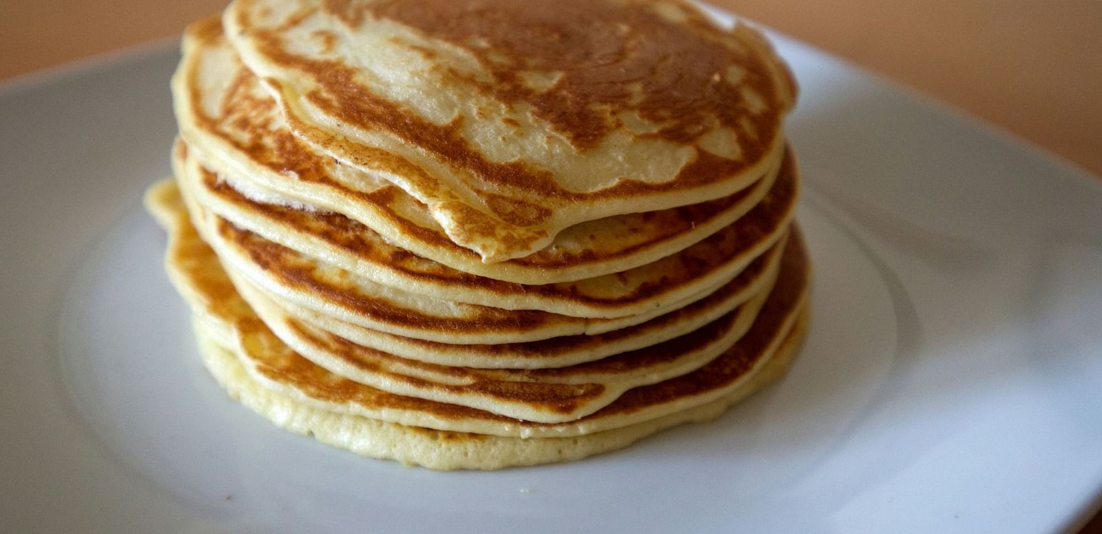 A stack of fluffy pancakes on a white plate.