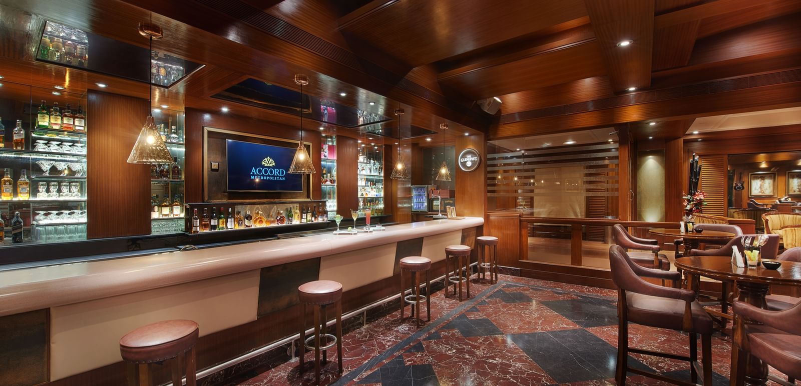 An image of a bar featuring many liquor products on the cabinets and shelves and a seating area with sofa chairs, chairs, and tables - Accord Hotels and Resorts