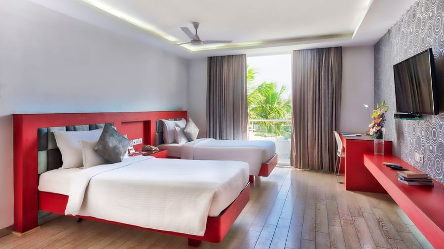 A modern hotel bedroom with a white bed, red frame, and a large window with white curtains | Grande Chalet | Grande Bay Resort & Spa, Mamallapuram