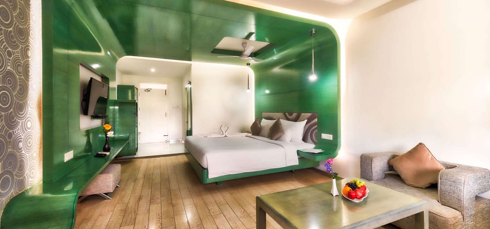 A room with king size bed, green wall panel and seating area at Grande Bay Resort & Spa.