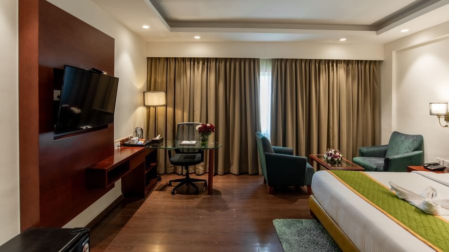 Spacious room with king size bed, television, and wooden flooring at Hotel Royal Regency Chennai