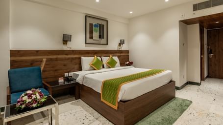 Spacious room with double bed, chairs, and bedside lamps at Hotel Royal Regency Chennai