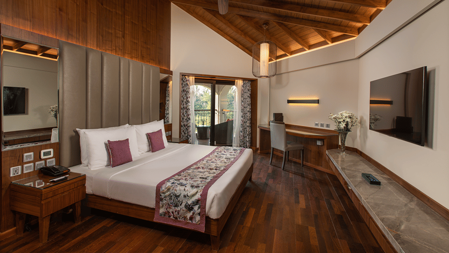 Pool View Suite King Bed looks neat in a mostly-white bedding surrounded by white walls and wooden furnishing at Kenilworth Resort & Spa, Goa