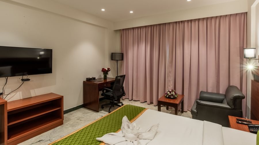 Well-furnished guest room with king size bed, sofa, and bedside lamps at Hotel Royal Regency Chennai