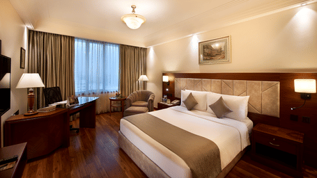 The Superior Room featuring a bed, a sofa chair, bedside table, and a work desk and chair in Accord Metropolian.