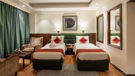 Room with twin beds, armchairs, and framed artwork at Hotel Royal Regency Chennai