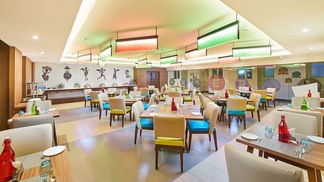 The warmly lit dining area has seats and tables set and ready for guests
