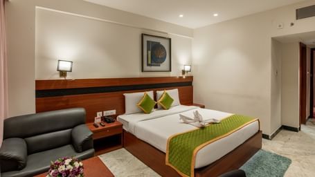 Bedroom featuring a comfortable bed, armchair, and warm lighting at Hotel Royal Regency Chennai