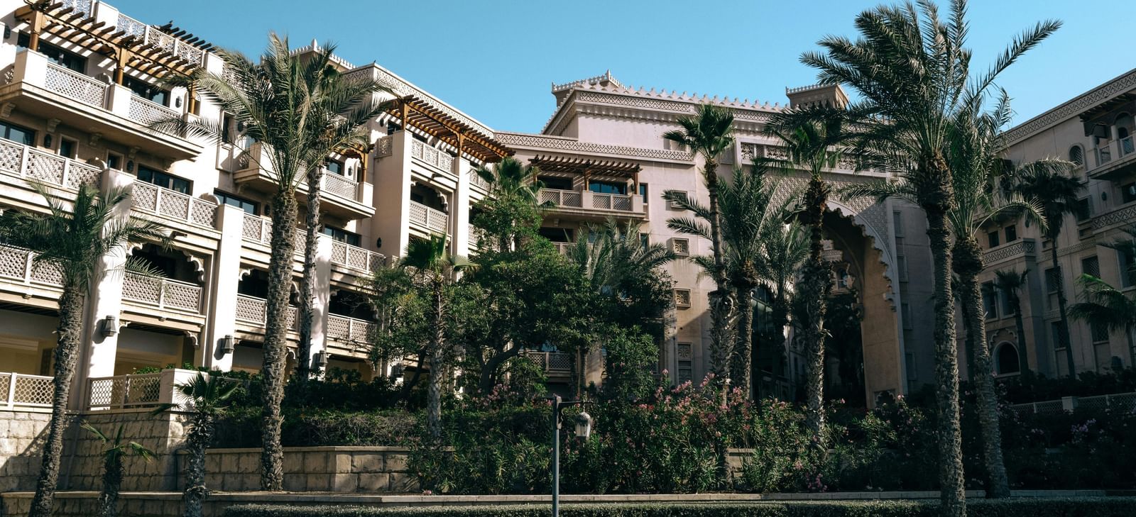 An exterior view of a residential or resort building with palm trees and balconies.