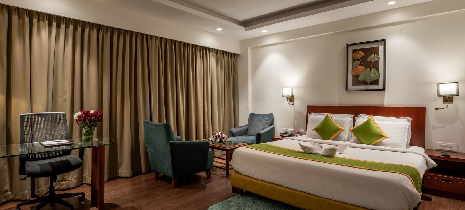 Bedroom with work desk, armchairs, and elegant curtains at Hotel Royal Regency Chennai