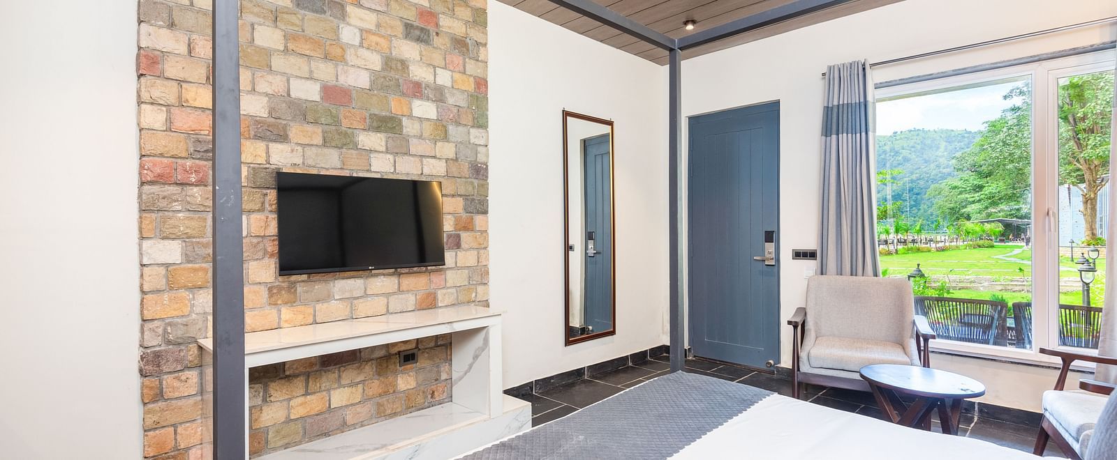 Closeup view of Luxury Cottage at DLS Divine River Resort and  Spa featuring a king size bed with mirror, TV and a chair.