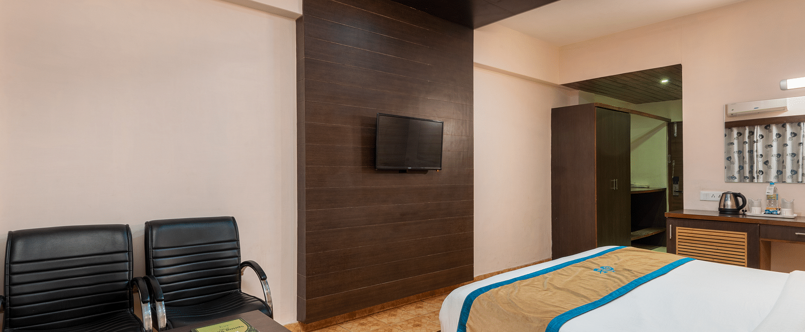 A Deluxe Non view room at DLS Spring Valley resort  Dharamshala featuring a  king bed, table, chairs and a TV