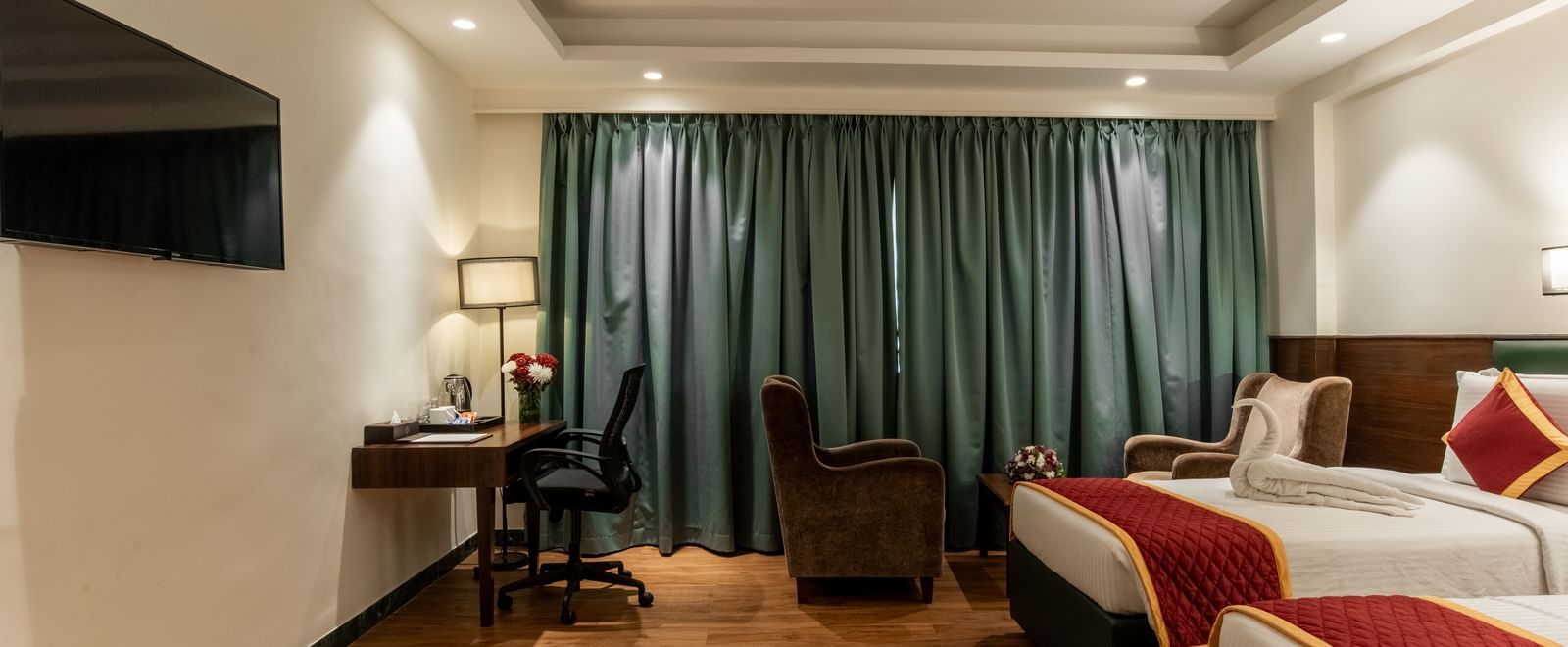 Twin bedroom with curtains and reading lamp at Hotel Royal Regency Chennai