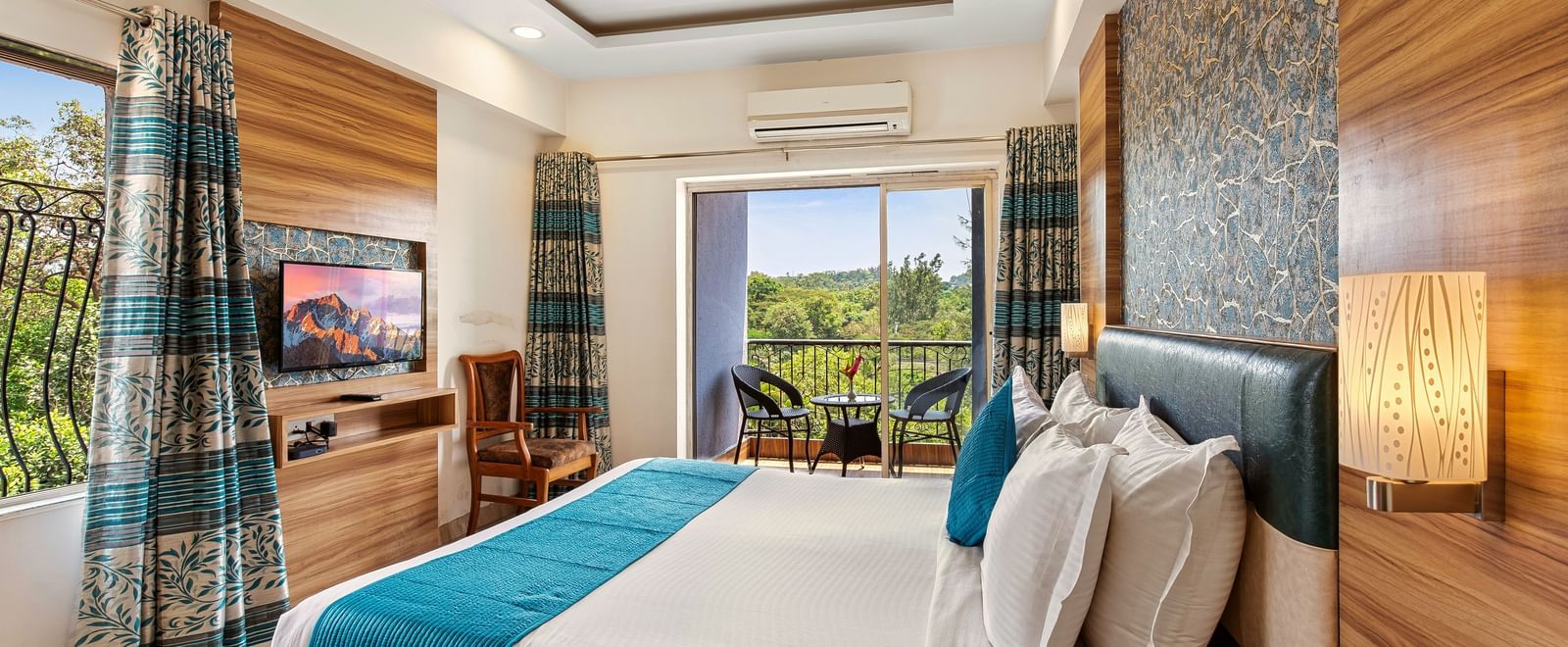 Comfortable bedroom at Mayur Retreat with natural light, blue curtains, and a view of the greenery outside.