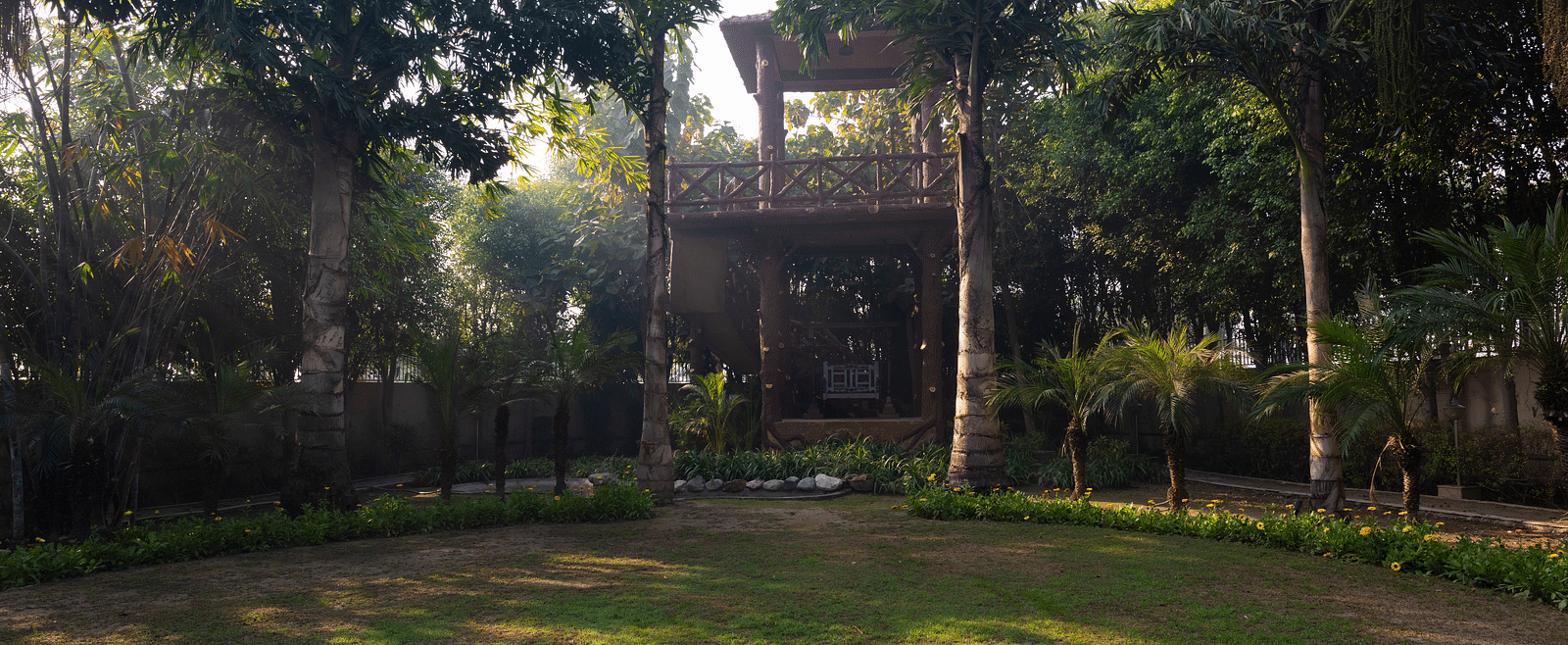 An image of a garden surrounded by tall trees at BluSalzz Resort.